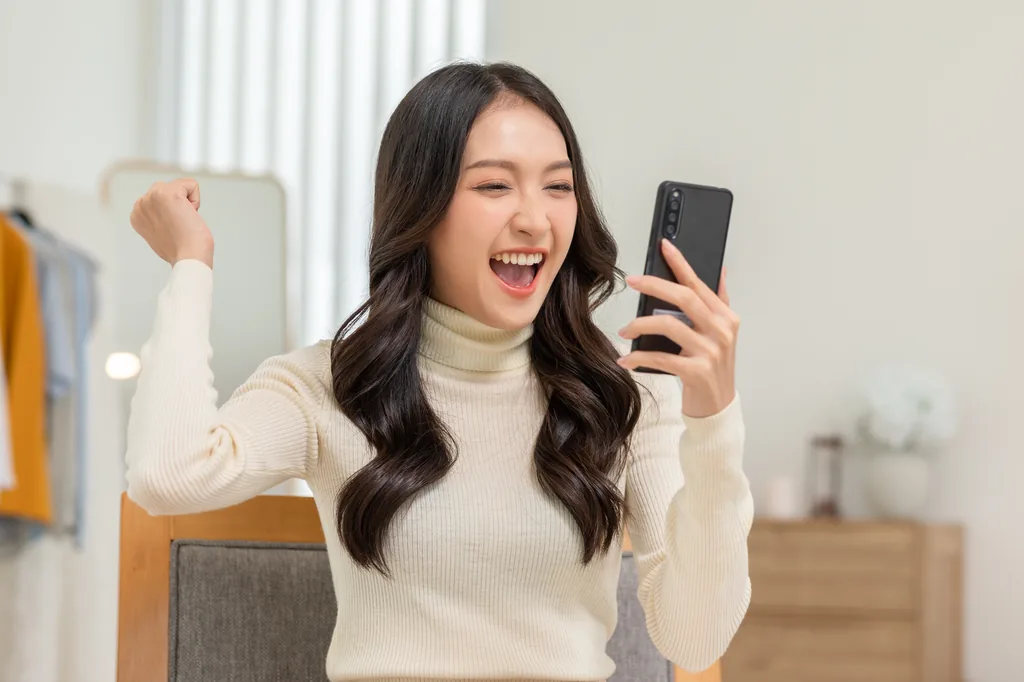 Phụ nữ Việt vui mừng kiểm tra ứng dụng đầu tư ở Mỹ trên điện thoại