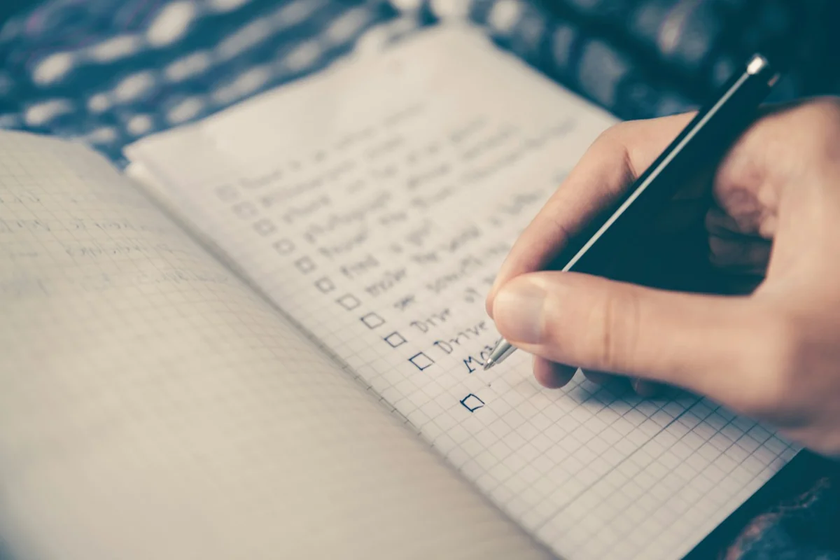Tay đang ghi các đầu mục vào sổ checklist